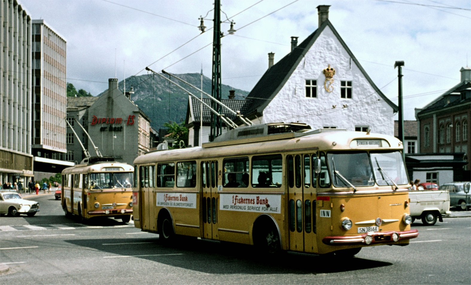 Åke Nergell er en svensk tog/trikk/bussentusiast som besøkte Bergen i juli 1973. Et av de mange bussituasjonene han foreviget var disse to trolleybussene av type Skoda. Det er SN 38144 i front fulgt av SN 38240. Trolleybussene fra Tsjekkoslovakia ble satt inn på linje 2, Natlandsveien - Engen i 1972, da de gamle Sputnikene, Sunbeam med Munck karosseri ble sjaltet ut. (Se RUTEBIL nr 84.) Motivet er hentet fra Småstrandgaten, like foran det gamle Rådhuset i Bergen. Skodatrolleybussene var egentlig museale allerede ved innsatsen, både teknologisk og utseendemessig. En av Skodaene er tatt vare på, og befinner seg nå på Bergen Tekniske Museum på Møhlenpris. Den er ikke ferdig restaurert.