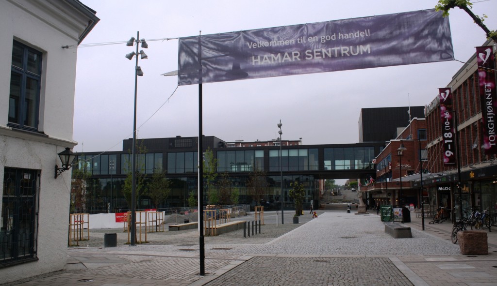Dette er fra andre enden av Torggata og vi ser inn på Stortorget i Hamar. Hamars nye kulturhus er nettopp innviet, men det gjenstår enda noe arbeid før torgplassen er ferdig. Til venstre ser vi hjørnet av Stallgården som har vært der siden 1849. Rundt Stortorget er det nå bygninger fra alle epoker av byens historie.